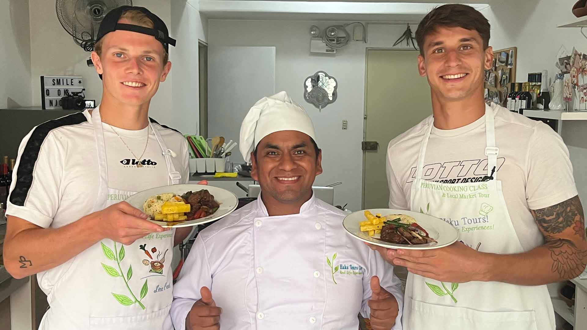 <a href='https://www.atptour.com/en/players/jesper-de-jong/d0c1/overview'>Jesper de Jong</a> (left) and <a href='https://www.atptour.com/en/players/camilo-ugo-carabelli/u182/overview'>Camilo Ugo Carabelli</a> pose with the chef after cooking lomo saltado.