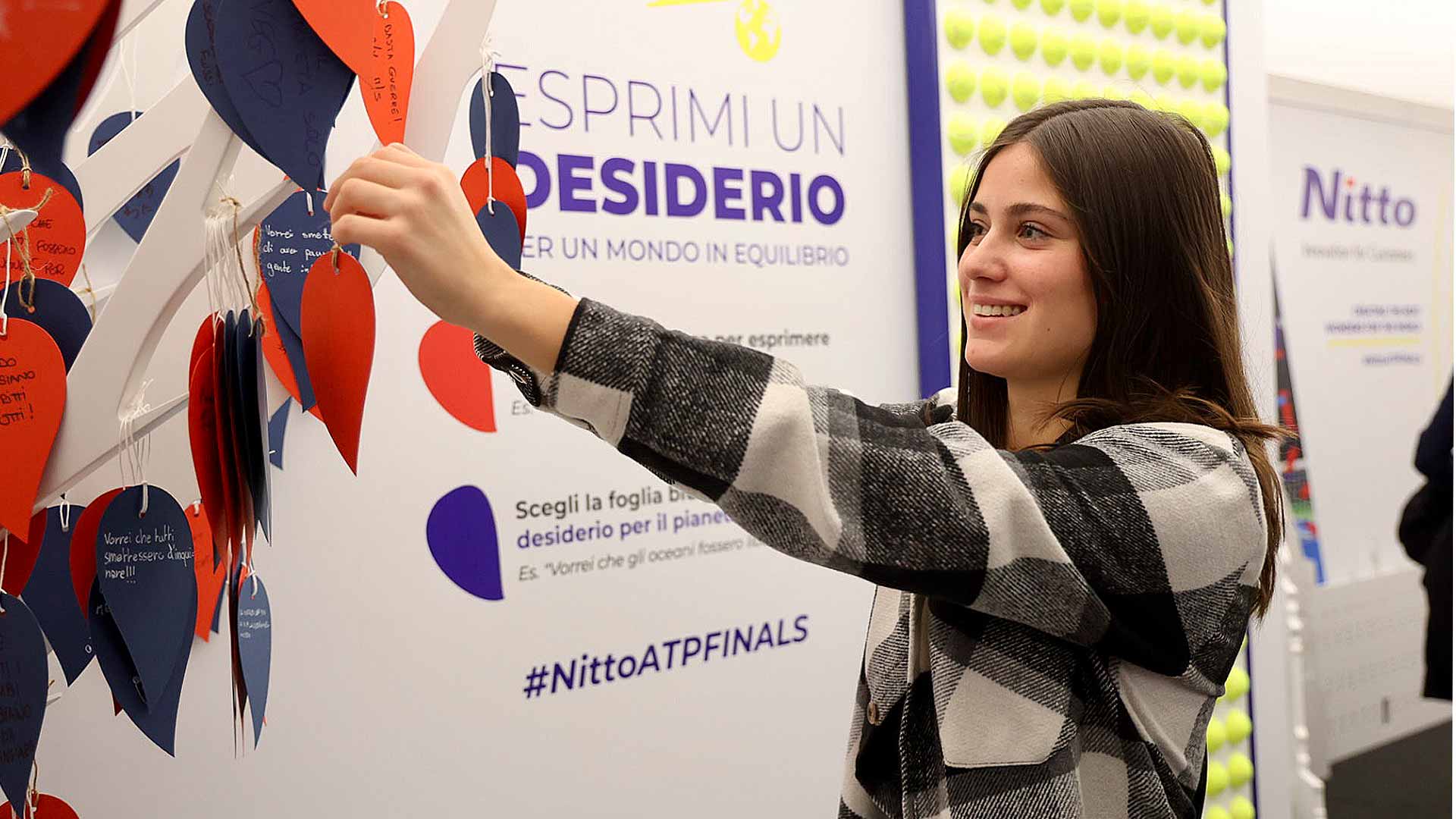 Un fan cuelga un mensaje positivo de sustentabilidad en el Future Wish Tree de Nitto.