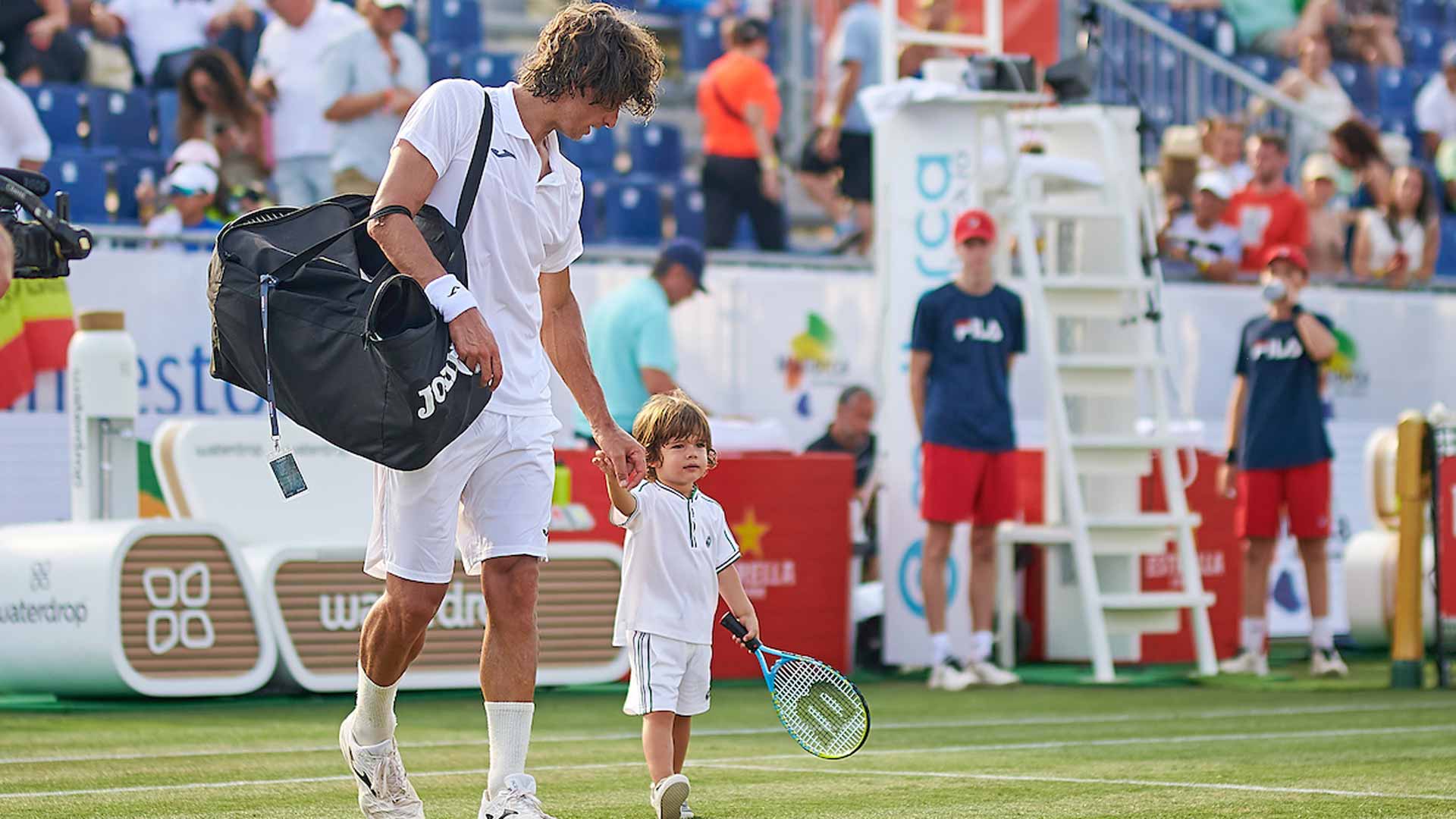 Feliciano Lopez walks off court with his son Dario at the Mallorca Championships.