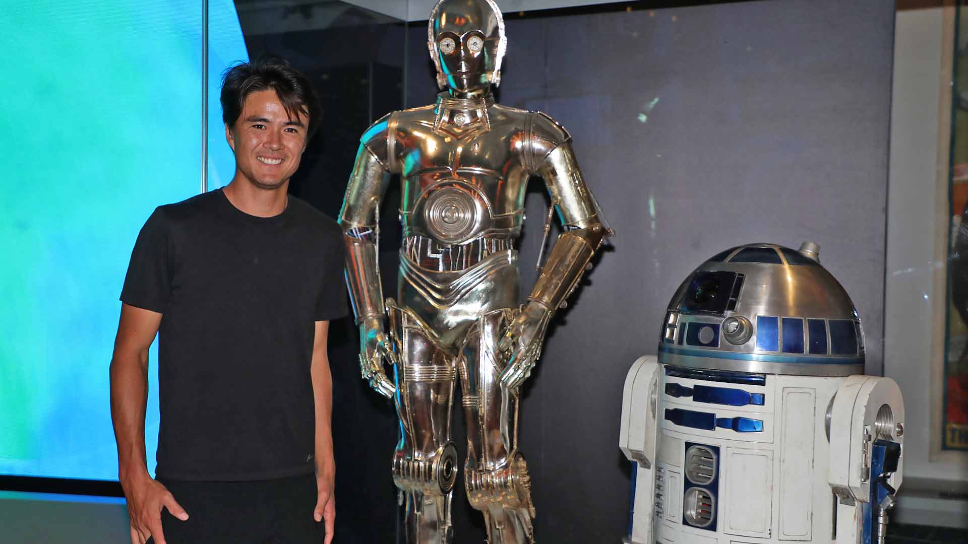 Taro Daniel poses with C-3PO and R2-D2 from Star Wars at the National Museum of American History.