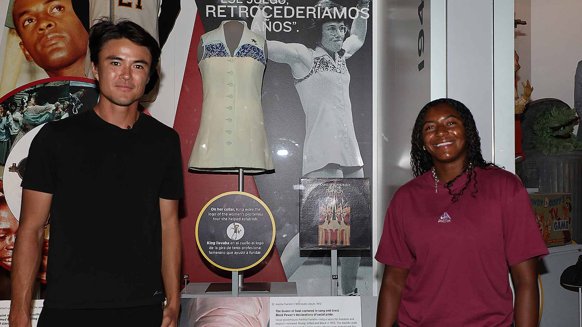 Taro Daniel and Hailey Baptiste pose with Billie Jean King's kit from the 1973 Battle of the Sexes match at the National Museum of American History.