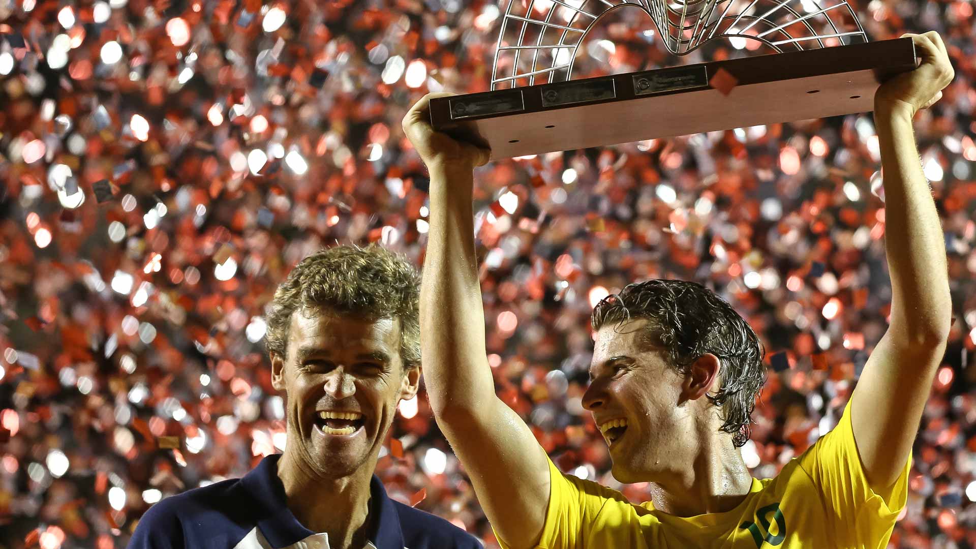 Former World No. 1 <a href='https://www.atptour.com/es/players/gustavo-kuerten/k293/overview'>Gustavo Kuerten</a> and <a href='https://www.atptour.com/es/players/dominic-thiem/tb69/overview'>Dominic Thiem</a> share a laugh at the 2017 Rio Open trophy ceremony.