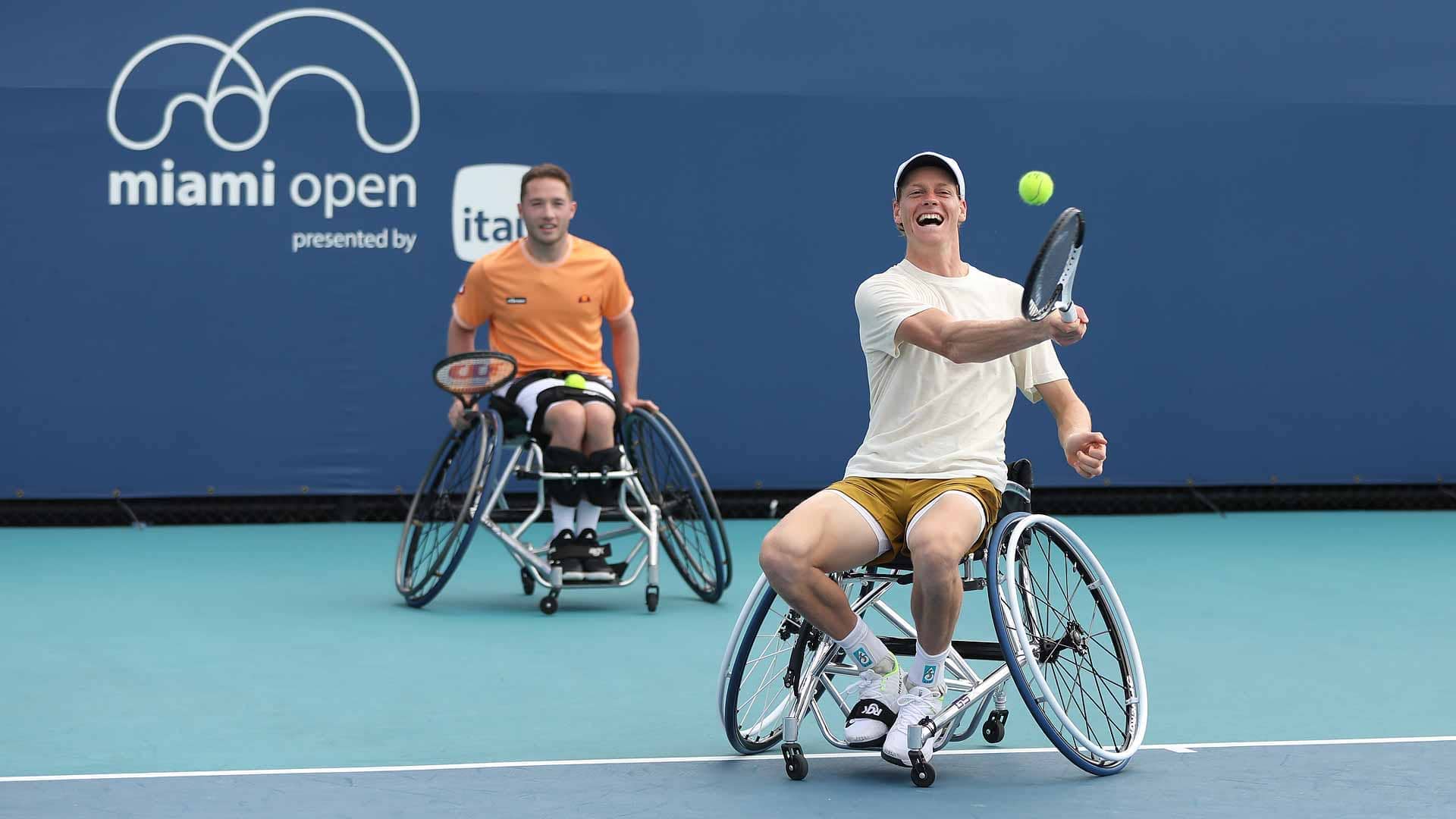 Jannik Sinner hits a forehand as Alfie Hewett looks on in Miami.