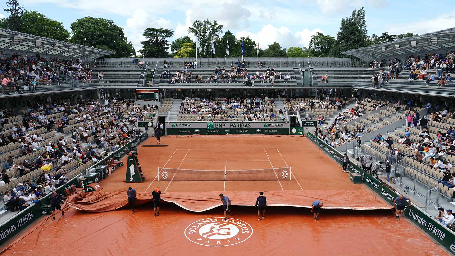 Ground staff remove the covers at Roland Garros.
