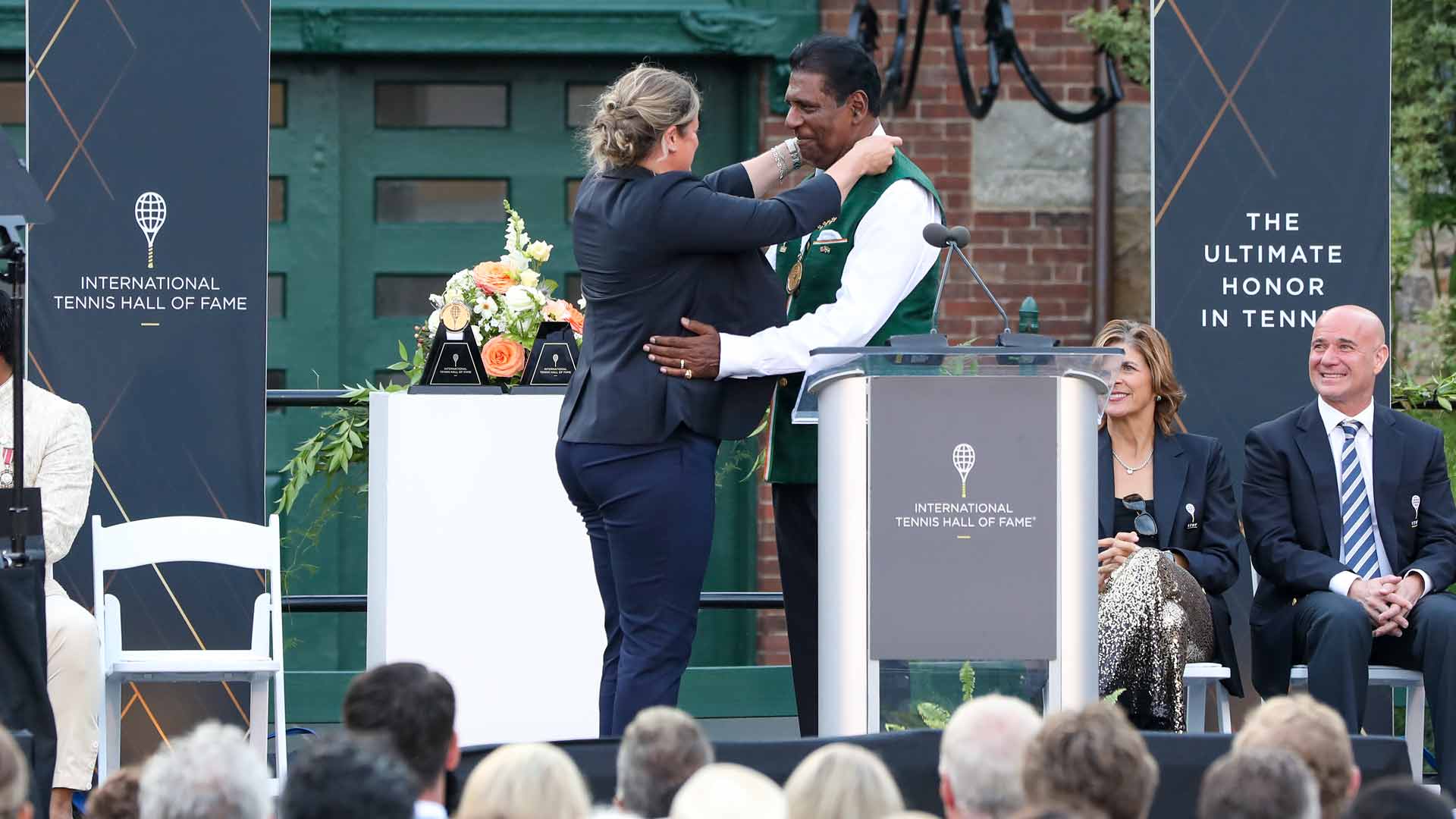 International Tennis Hall of Fame Honourary President Kim Clijsters presents Vijay Amritraj with a medal upon his induction Saturday in Newport.