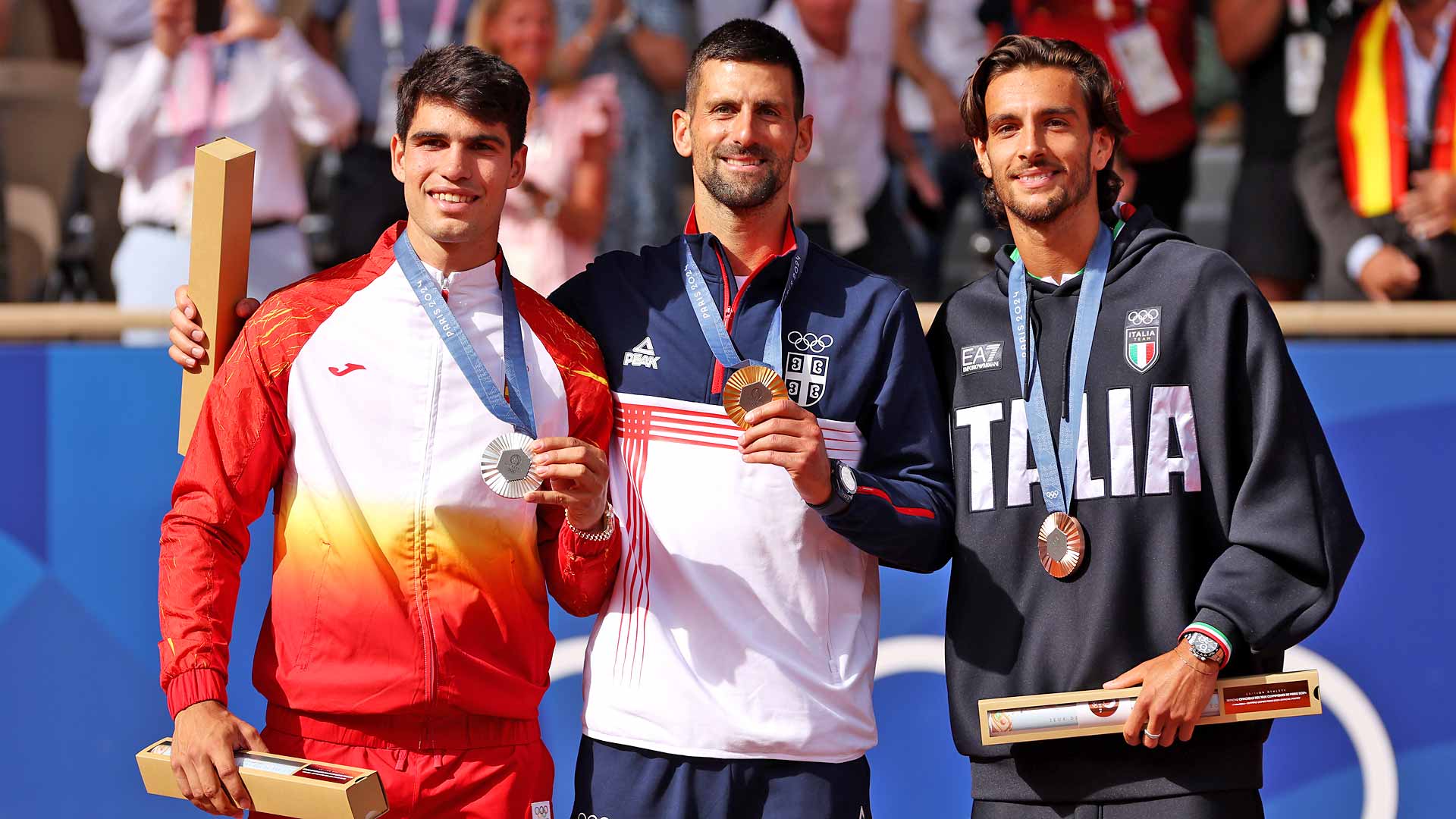 Carlos Alcaraz, Novak Djokovic and Lorenzo Musetti stand on the podium Sunday at the Paris 2024 Olympic Games.