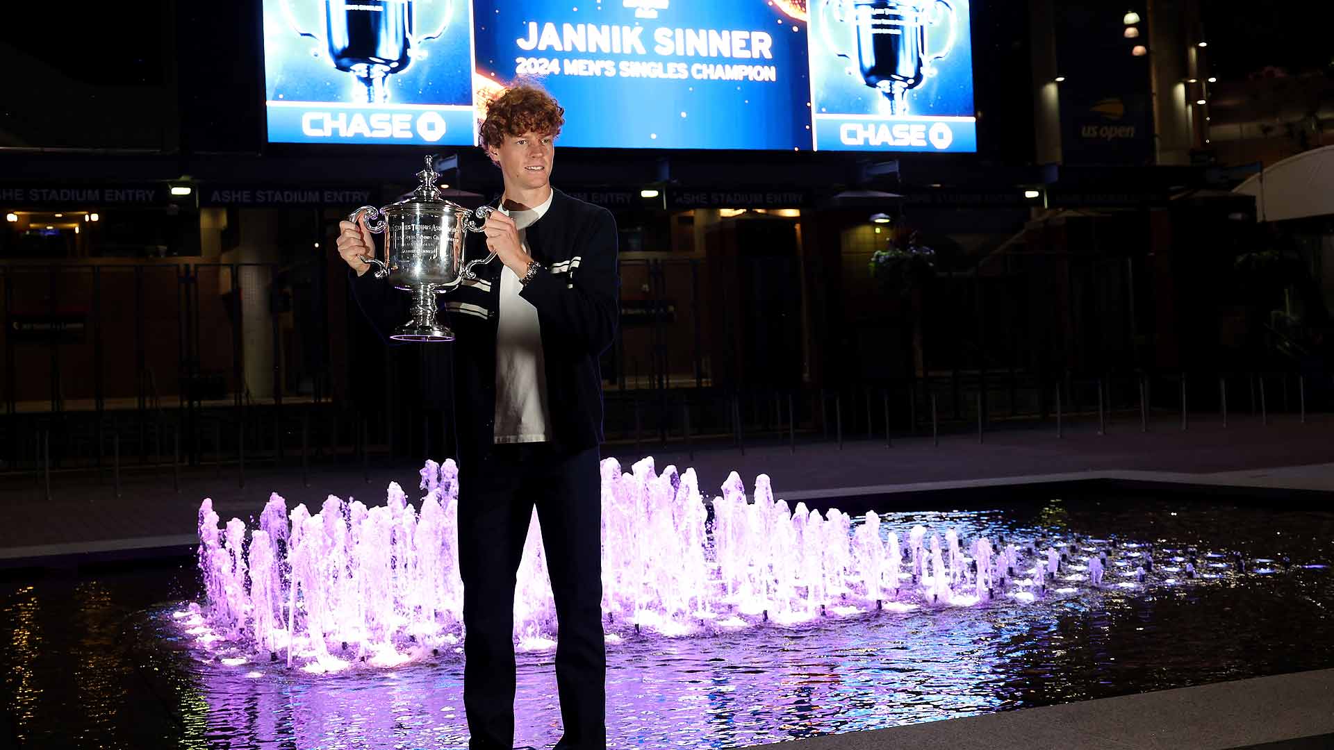 Jannik Sinner celebrates his first US Open title in front of Arthur Ashe Stadium.