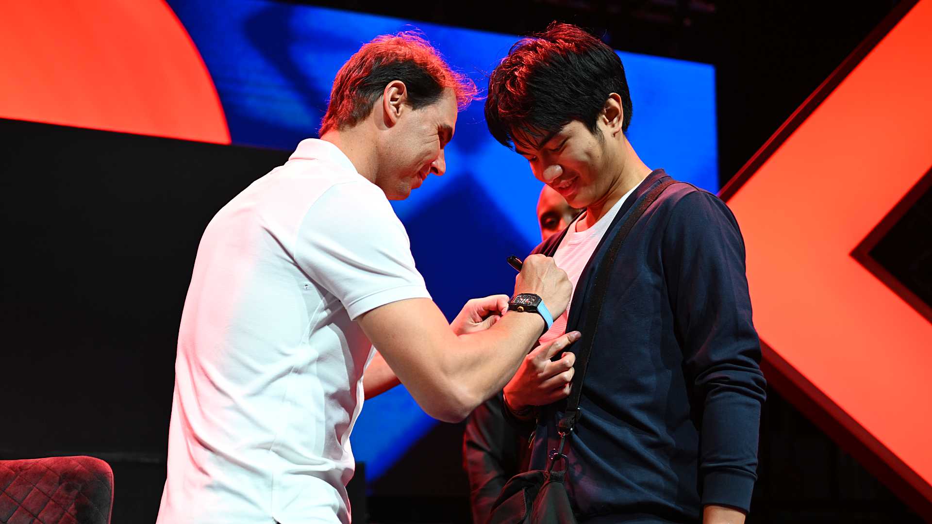 Nadal signs a fan's shirt in the fan zone.