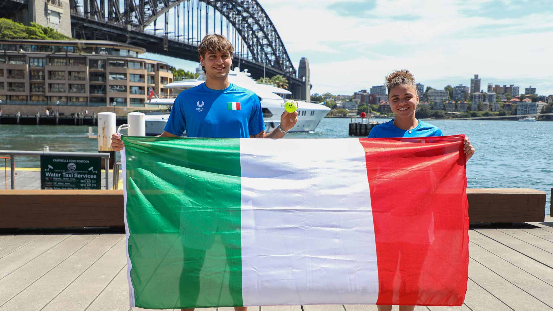 <a href='https://www.atptour.com/en/players/flavio-cobolli/c0e9/overview'>Flavio Cobolli</a> and Jasmine Paolini pose in front of Sydney Harbour Bridge ahead of the 2025 <a href='https://www.atptour.com/en/scores/archive/perth-sydney/9900/2025/results'>United Cup</a>.