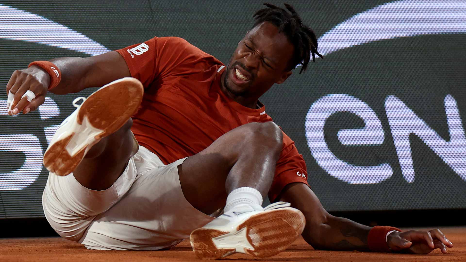 Monfils crashes into court signage, battles back to win five-setter at Roland Garros