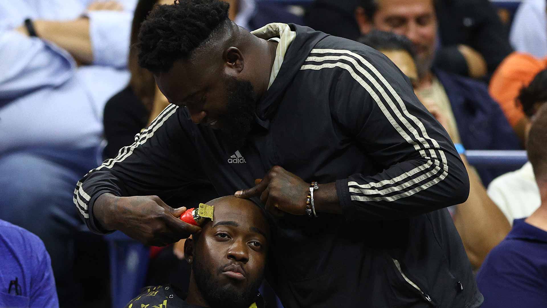 A man in the second row of Arthur Ashe Stadium receives a haircut during Khachanov-Kyrgios Tuesday night.