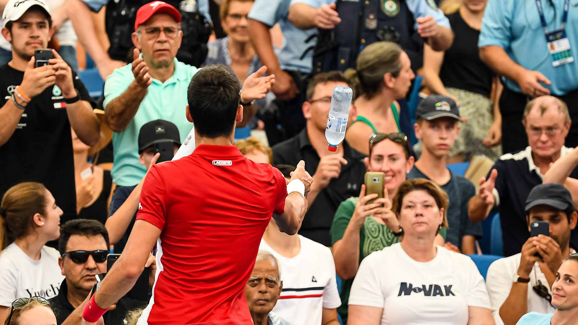 Novak Djokovic helps a fan during the third set of his ATP Cup quarter-final match against Denis Shapovalov on Thursday.
