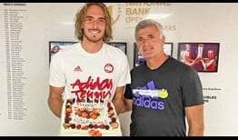Stefanos Tsitsipas and his father, Apostolos Tsitsipas, pose with a cake Toronto tournament organisers gave Stefanos for his 23rd birthday.