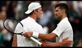 Tim van Rijthoven y Novak Djokovic hablan en la red tras disputar los octavos de final de Wimbledon.