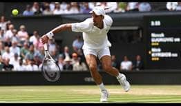 Novak Djokovic approaches the net with a backhand slice during the Wimbledon final.