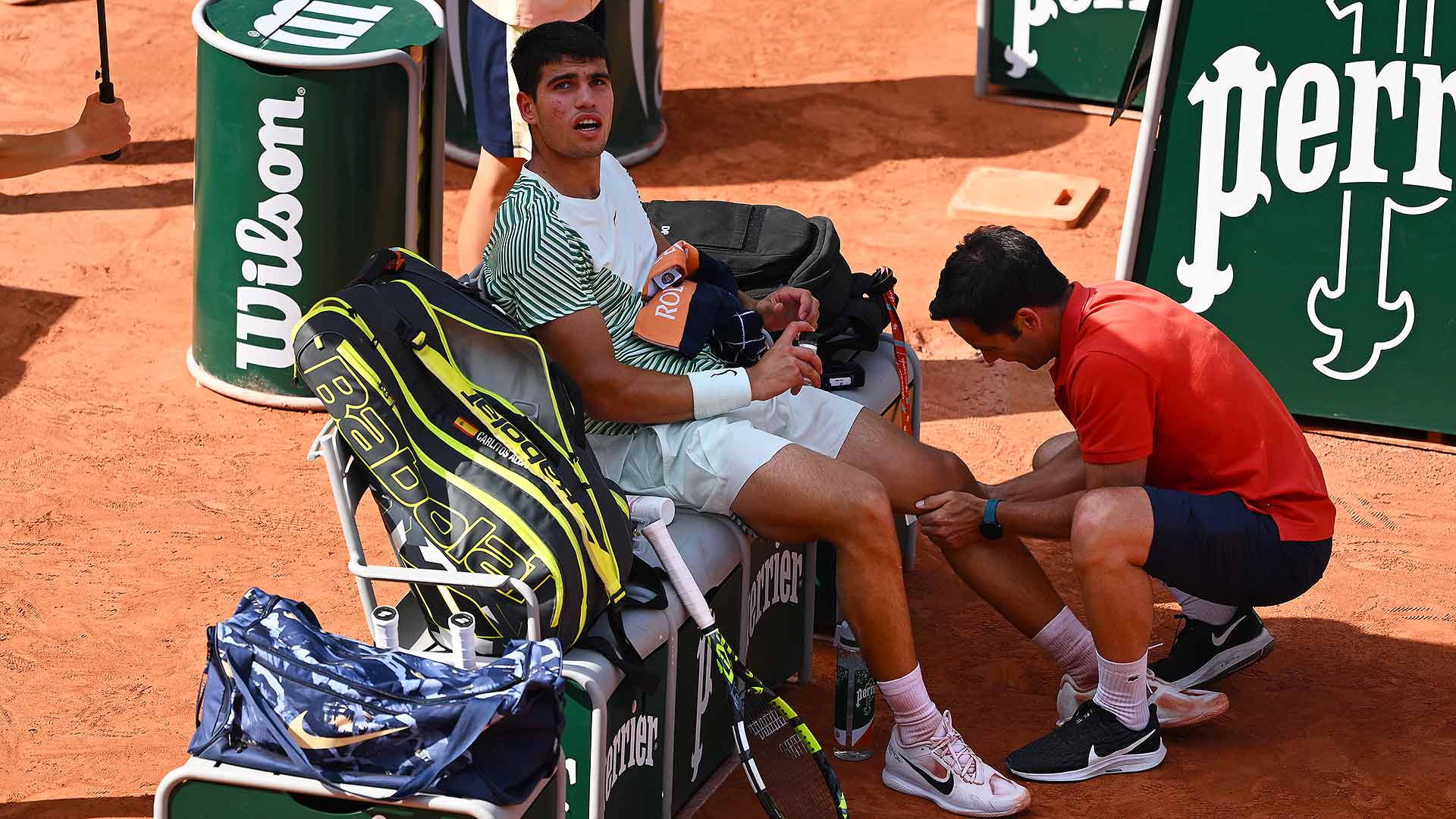 Carlos Alcaraz receives treatment for leg cramps during his Roland Garros semi-final against Novak Djokovic.
