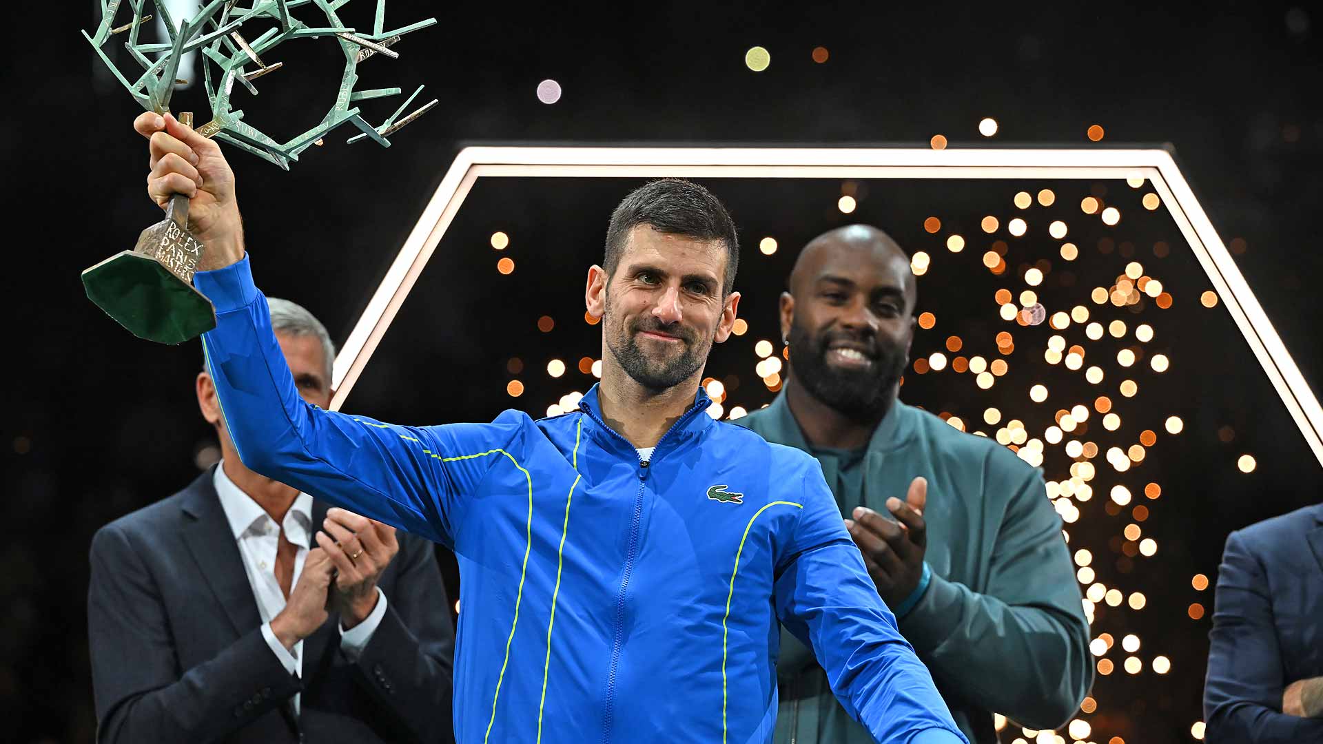 Novak Djokovic celebrates after receiving the Rolex Paris Masters trophy on Sunday from French Olympic judoka Teddy Riner.