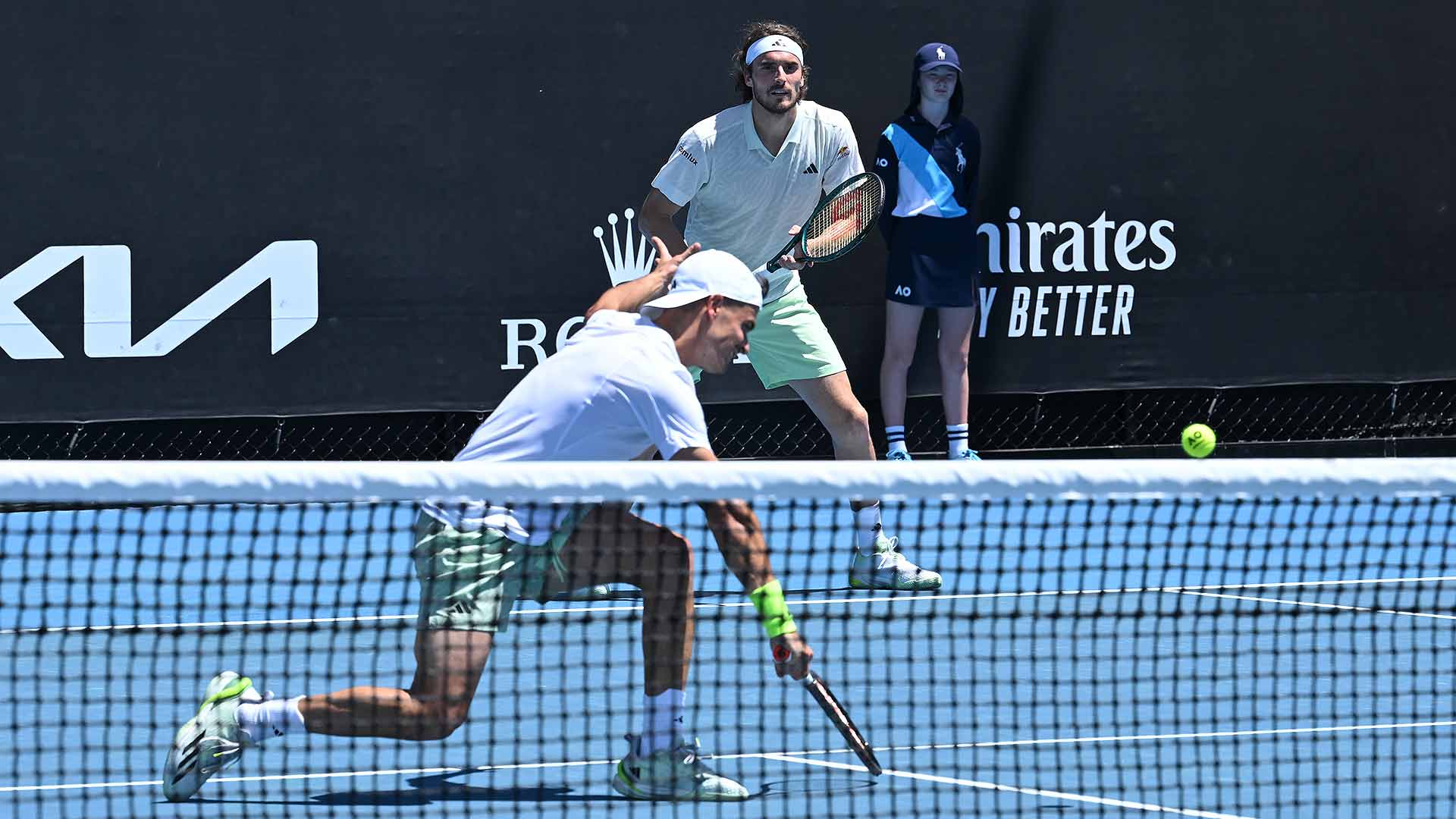 Petros Tsitsipas (at net) and Stefanos Tsitsipas fall on the first day of doubles play at the Australian Open Tuesday in Melbourne.