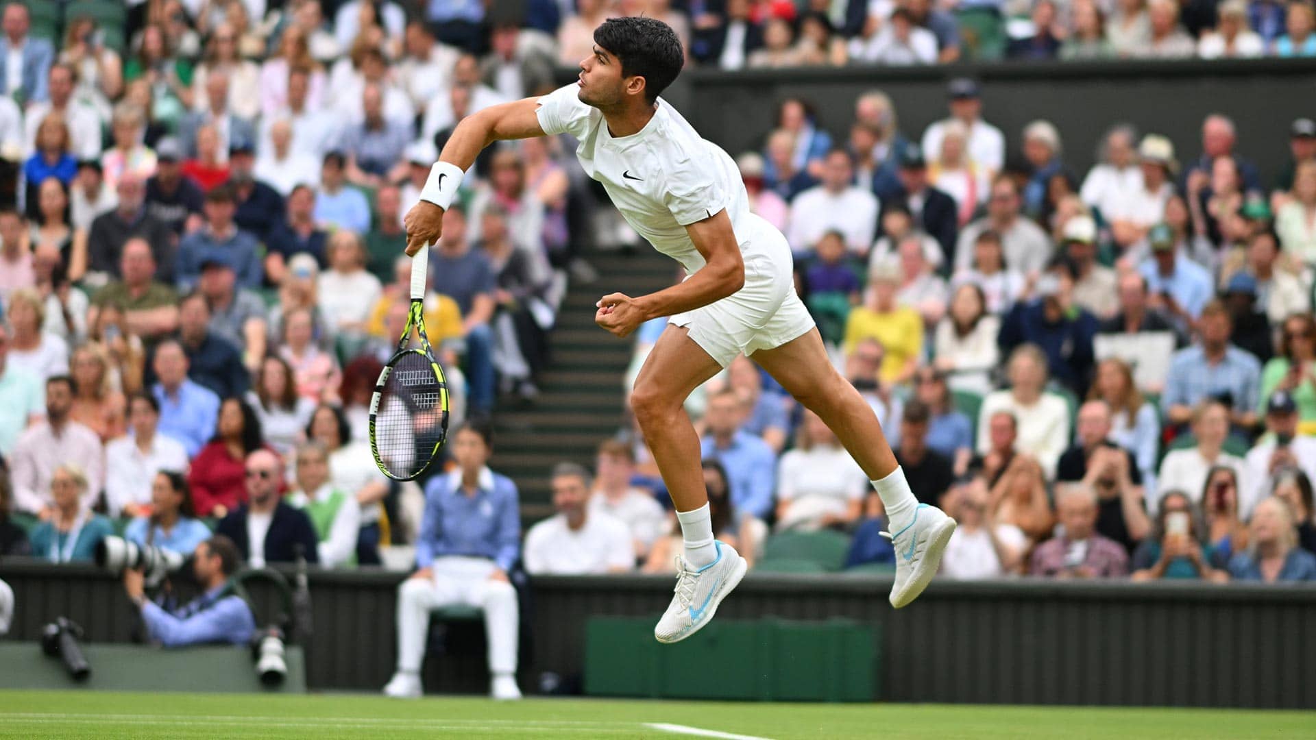 Carlos Alcaraz serving against Frances Tiafoe at Wimbledon.